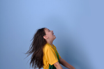menina sorridente usando camisa do brasil em fundo azul 