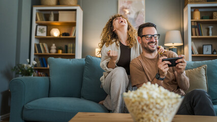 couple man and woman husband wife play smart phone video games at home