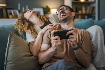 couple man and woman husband wife play smart phone video games at home