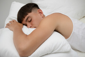 Fototapeta na wymiar Young Man Sleeping on Top of Bed