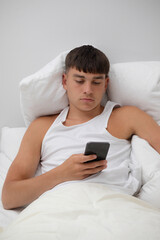 Young Man in Bed Using A Phone