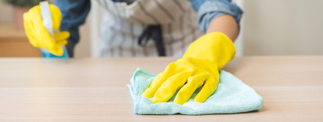 Cleanliness asian young woman working chore cleaning on table at home, hand wearing glove using rag...