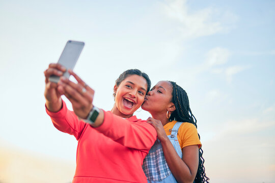 Selfie, kiss and friends posing together outdoor during summer to update a profile picture or status. Photograph, love and bonding with excited young women posting to social media while in nature