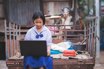 Asian female student in uniform learning using laptop computer in rural area of Thailand.Education...