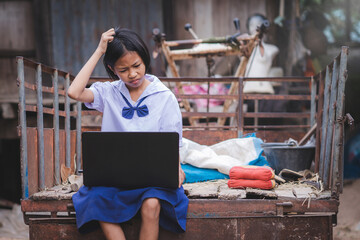 Asian female students in uniforms having trouble using laptop computers in rural area of Thailand.Education and technology use concept