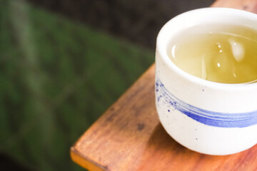 Cold Japanese green tea served in oriental classic cup or ceremic mug. Japanese ocha on wooden table in a restaurant. Asian herbal traditional drinks.