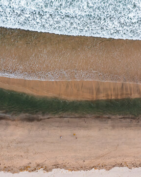 Aerial view of people along the the shoreline on the beach in Vila do Conde, Porto, Portugal.