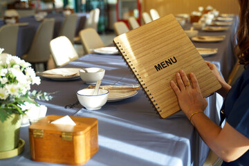 A Thai woman in a restaurant while waiting for friends to have dinner together. She chooses a menu and orders food that she and her friends like before friends arrive so they can eat.