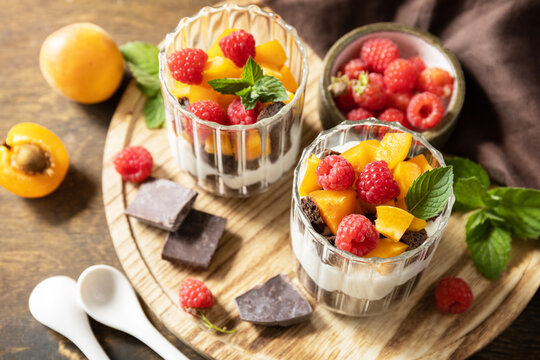 Triffle of chocolate biscuit with yogurt and fresh berries and fruits. Two portioned glass parfafait dessert. Summer healthy diet breakfast, snack concept.