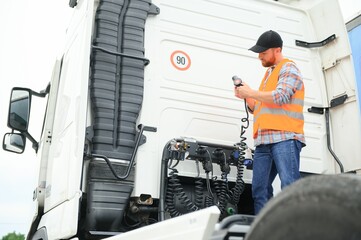 View of a driver connecting the power cables to trailer of a commercial truck.