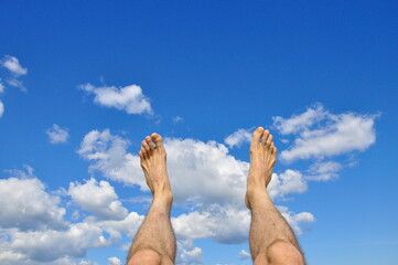 Business person jumping over clouds in the blue sky.