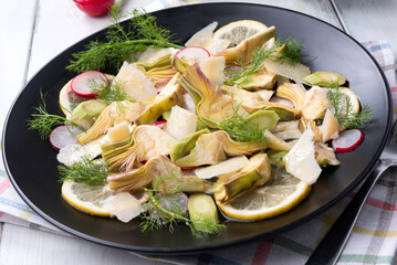Piatto di deliziosa insalata di carciofi, ravanelli e scaglie di parmigiano, cibo vegetariano italiano 