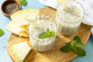 Cold fresh melon smoothies with chia seeds on wooden board on a stone background. Summer drink beverage, healthy food concept. Fresh seasonal smoothies.