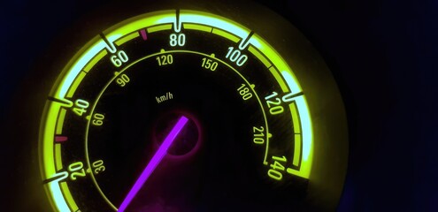 A car speedometer rev counter, lit up at night