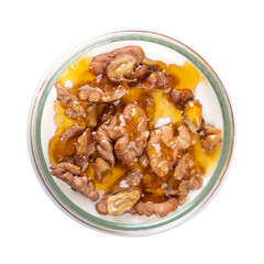 Greek yogurt with honey and roasted walnuts, in a glass jar. Yiaourti me meli, a traditional little treat, dessert and snack, made of stirred, creamy yogurt, with honey and walnut topping. Food photo.
