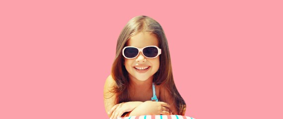 Summer vacation, happy smiling child little girl lying on pillow in sunglasses on pink background