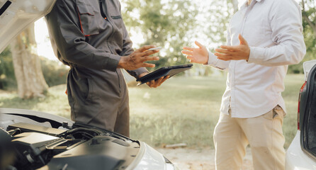 Naklejka premium Young mechanic opens the bonnet to inspect the engine for damage and does professional maintenance. He puts on his uniform and inspects. 