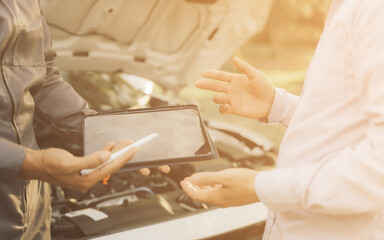 Obraz premium Young mechanic opens the bonnet to inspect the engine for damage and does professional maintenance. He puts on his uniform and inspects. 