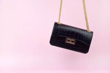 Black women's handbag on a pink background, minimalist.