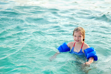 Fototapeta na wymiar Niña hermosa feliz rubia latina alegre divertida jugando en el agua en la alberca piscina en el verano y disfrutando de un día soleado al aire libre