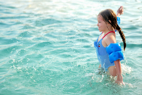 Ni&ntilde;a hermosa feliz rubia latina alegre divertida ba&ntilde;andose y jugando en el agua en la alberca piscina en el verano mojandose salpicando saltando y disfrutando de un d&iacute;a soleado al aire libre