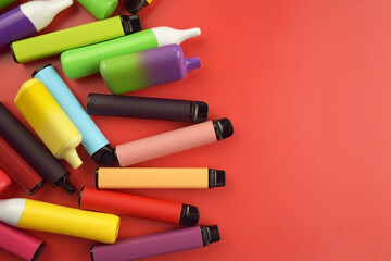 Set of multicolor disposable electronic cigarettes on a red background.