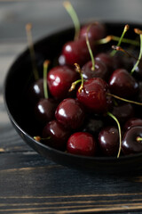 Cherries in a black bowl on a dark wooden background