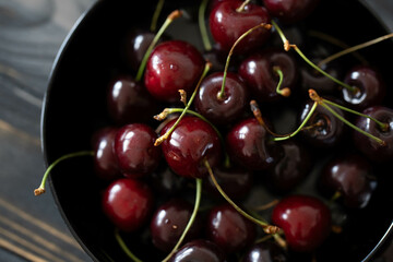 Cherries in a black bowl on a dark wooden background