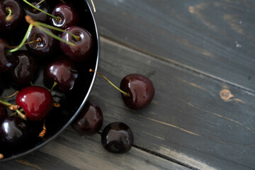 Cherries in a black bowl on a dark wooden background