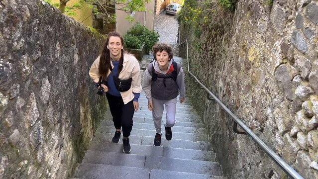 Two travellers climb stairs in an old french town