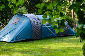 Campground in the shade of green trees on a sunny summer day. Extreme sports and outdoor recreation. tourist tent