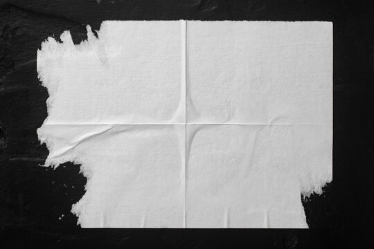 White paper with folds on a black wall. © Yevhenii