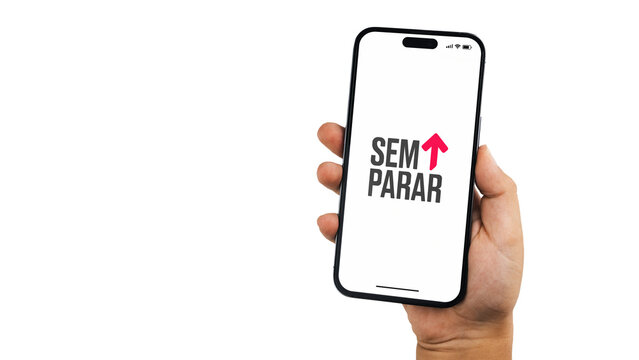 Boy holding a smartphone iPhone 14 Pro with Sem Parar app on the screen. White background. Rio de Janeiro, RJ, Brazil. July 12 2023.
