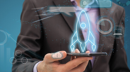 Startup concept with businessman holding tablet or smartphone transparent rocket in launching with network connection on modern virtual interface.StartUp Programming Team.Website designer working.