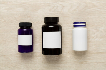 Plastic bottles with vitamins on wooden background, top view
