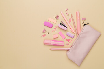 Pink pencil case with school stationery on color backgroung, top view