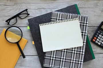 magnifier, glasses, folder with documents and notepad on a wooden table