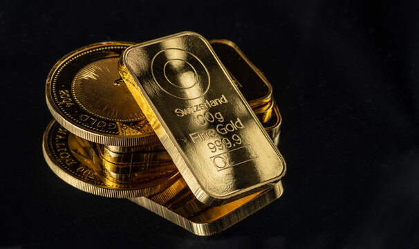 Gold bars and gold coins on a black background. Selective focus.
