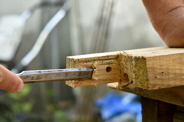 A carpenter breaks a piece of wood off a board with a chisel.