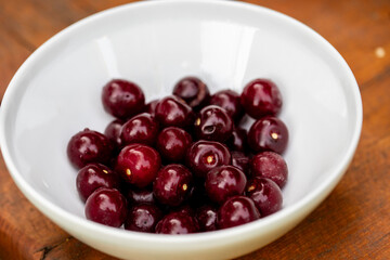 A white bowl of ripe sweet red cherries. Fresh sour cherries harvest.
