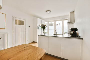 a kitchen and dining area in a house with white walls, hardwood flooring and an oven on the wall