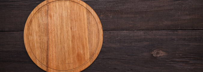 Round wooden cutting board on a wooden background