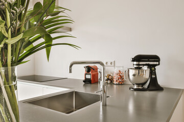 a kitchen counter with some flowers in the vase and an orange mixer on the countertop next to the...