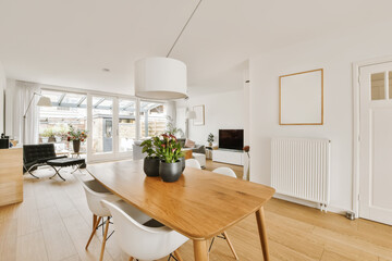 a dining room with white walls and hardwood flooring, including a large wooden dining table surrounded by two chairs