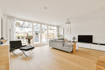 a living room with white walls and hardwood flooring, showing the natural light coming in through the sliding glass doors