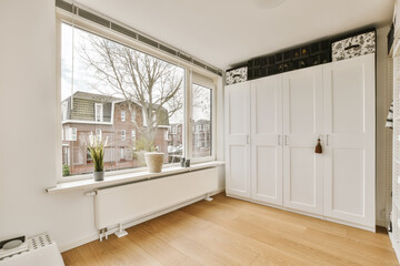 a room with wood flooring and white cupboards on either side of the window looking out onto the street