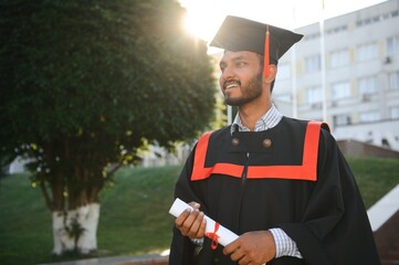 Portrait of indian handsome male graduate in graduation robe.