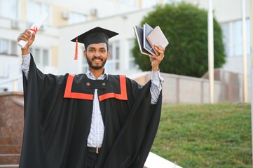 portrait of successful indian student in graduation gown.
