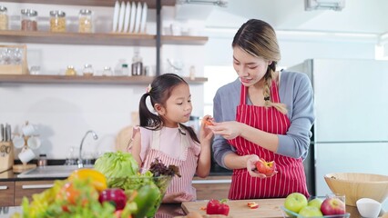 Young asian mother cutting apples to little daughter eating in kitchen room at home. Eating fruit for health care. Happy family, Healthy food
