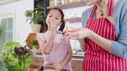 Fototapeta premium Happy little asian girl enjoy eating apples in kitchen room at home. Eating fruit for health care. Happy asian family, Healthy food concept